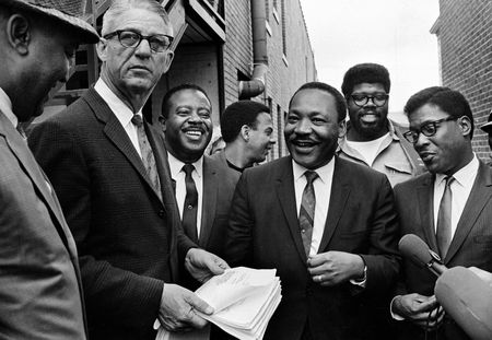 Martin Luther King Jr., center, and Rev. Ralph Abernathy, third from left, share a laugh outside court in Decatur, Ga., Oct. 25, 1960. Others are unidentified. Andrew Young is seen at center, facing right. (AP Photo)